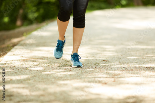 Cropped picture of female runner running in nature on sunny day. © Sanja