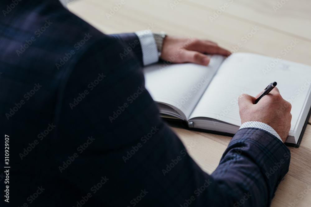 businessman in a jacket fills a diary sitting at a table businessman in a jacket fills a diary sitting at a table