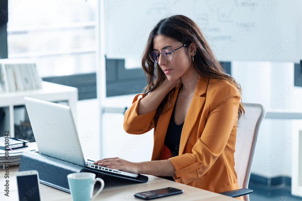 Business young woman with neck pain working with laptop in the office. Business young woman with neck pain working with laptop in the office.