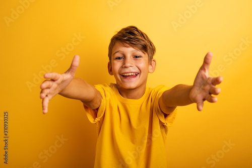 Happy and joyful child wants to hug someone. Yellow background color photo