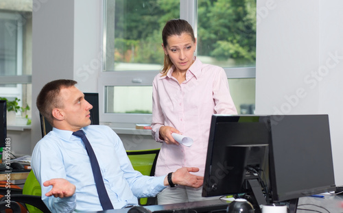 Female manager checks the work of a subordinate man, she is unhappy, he is to blame. The boss is outraged by the work of the office employee.