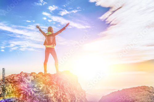 the girl stands on top of the mountain and enjoys the view of the valley. at the dawn, hands up