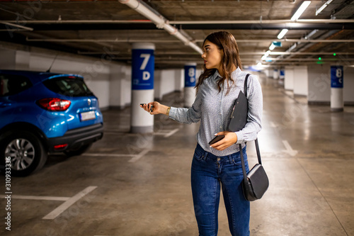 Photography Elegant businesswoman locking her car with keys in underground parking