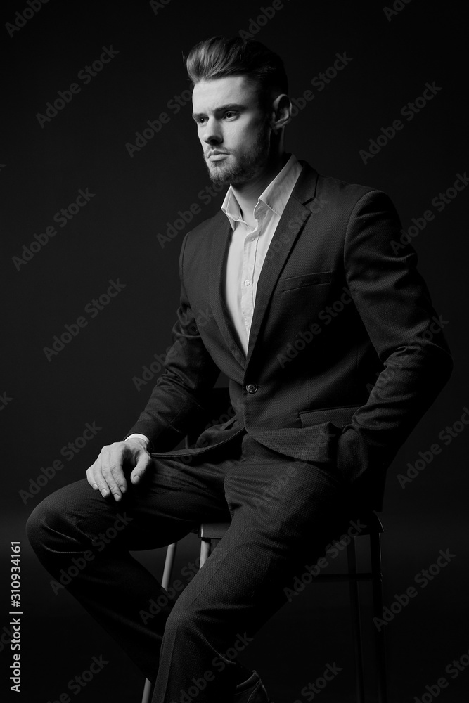 a young man in a suit. the man with the beard. Male portrait on a black background. Stylish man. black and white photo. male model. studio portrait. The guy in the classic suit