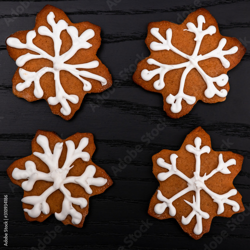 Homemade gingerbread cookies on black wooden background, snowflakes covered with white icing as a mininalistic concept of Christmas and new year on black wooden background photo