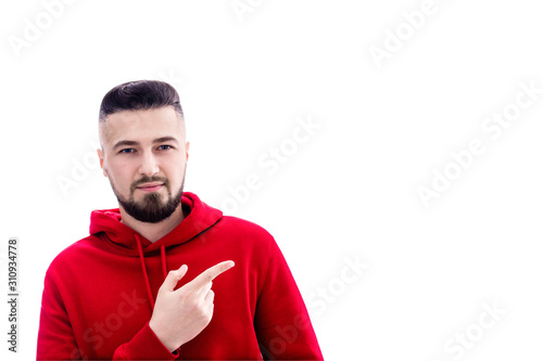 Handsome man in red casual clothes pointing his finger to the side on white background