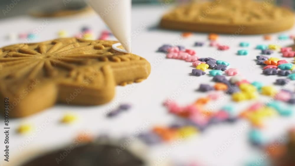 Putting sweet white cream on differents gingerbread cookies. Sweet Christmas holiday cookies with cream. Cooking yummy sweets in the bakery. 4k close up. Slow motion footage. Decoration of cookies. Putting sweet white cream on differents gingerbread cookies. Sweet Christmas holiday cookies with cream. Cooking yummy sweets in the bakery. 4k close up. Slow motion footage. Decoration of cookies.