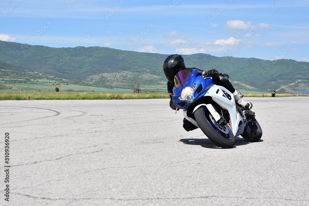 Young woman motorcyclist speeding on tarmac racetrack - former airport runway near the town of Dupnitsa, Bulgaria