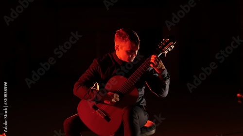 guitarist plays classical music on an acoustic guitar on a black background,isolated