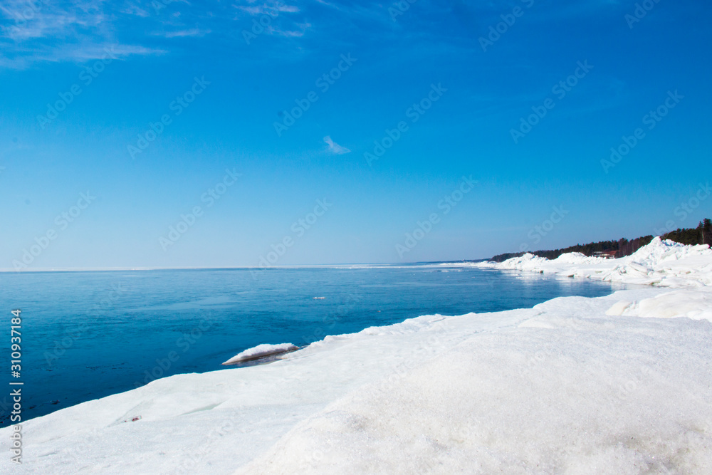 Beautiful winter landscape with blocks of ice, snows, blue sky, horizon. Bay in the winter. Travel concept. Nature concept. Winter scene - snowy plain in sunny day. Wonderland winter background.