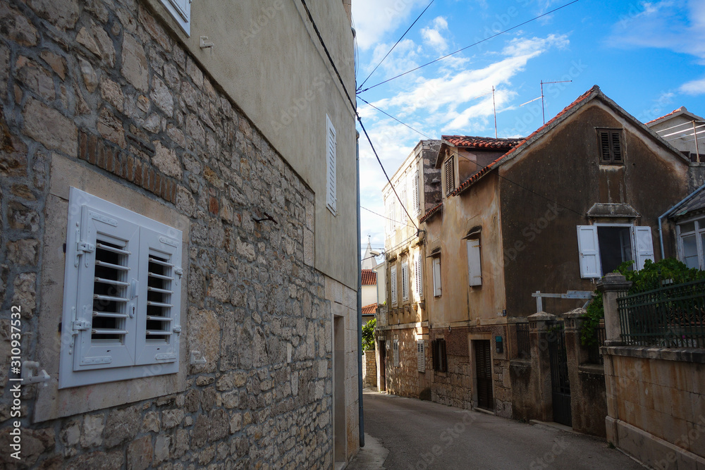 Supetar, Croatia / June 27th 2018: Stone houses and narrow streets in old town Supetar, Brac Island. Croatia, Europe