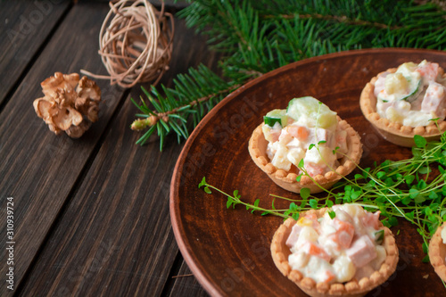 Russian traditional olivier salad in tartlets with potatoes, cucumber, egg, mushrooms and mayonnaise