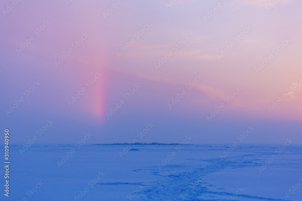 Winter evening landscape with snow-path and a sunny halo in the sky. Natural winter background. Winter pink and blue sunset