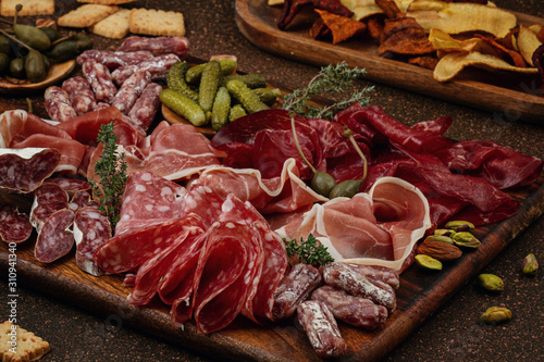Appetizers table with differents antipasti, cheese, charcuterie, snacks and wine. Sausage, ham, tapas, olives, cheese and crackers for buffet party. photo