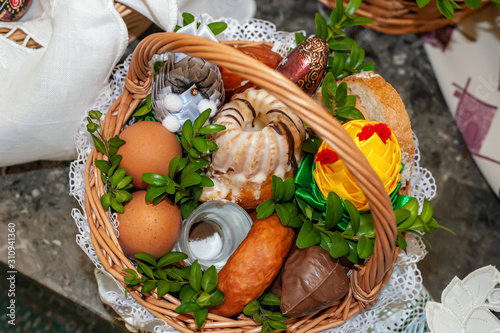 Decorated Easter basket filled up with every day food ingredients like eggs, bread, sausage, salt, sweets. Tradition of Easter in some cultures requires bringing it to church for blessing.