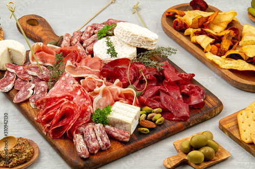 Appetizers table with differents antipasti, charcuterie, snacks and wine. Sausage, ham, tapas, olives, cheese and crackers for buffet party