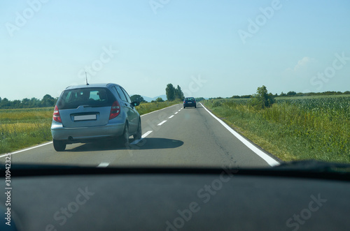 Cars on a road going through a countryside during a day