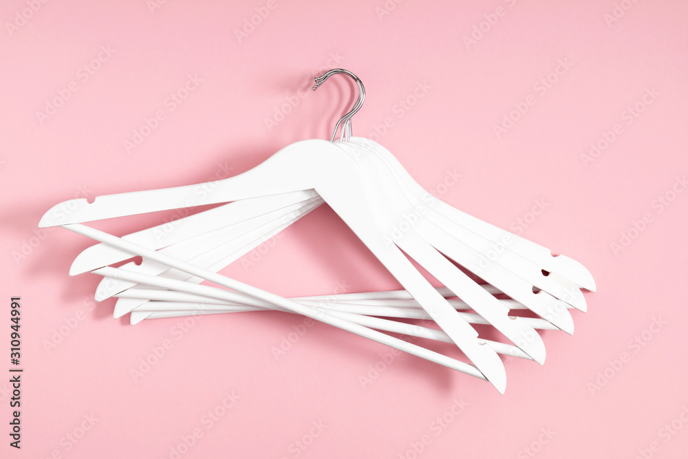 Wooden white hanger on pastel pink background. Flat lay, top view, copy space Wooden white hanger on pastel pink background. Flat lay, top view, copy space