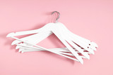 Wooden white hanger on pastel pink background. Flat lay, top view, copy space