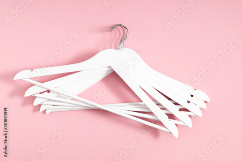 Wooden white hanger on pastel pink background. Flat lay, top view, copy space