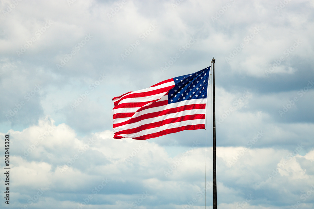 American Flag on Flagpole Against Cloudy Sky