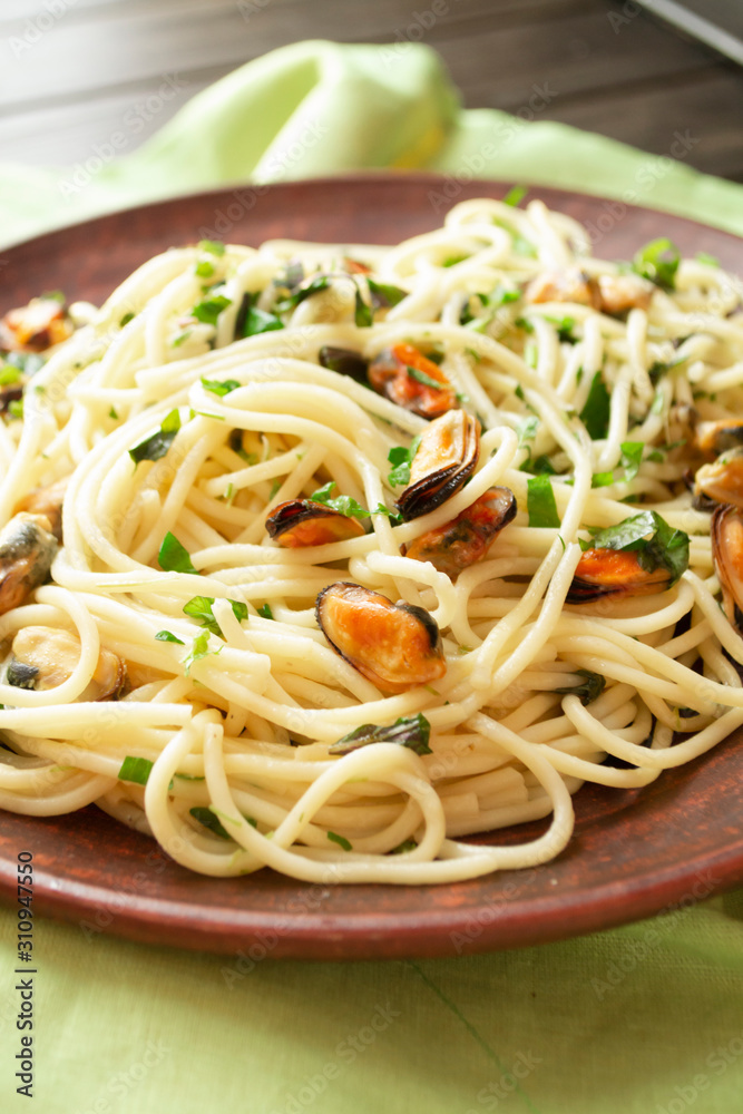 Spaghetti with mussels meat and herbs, vertical image