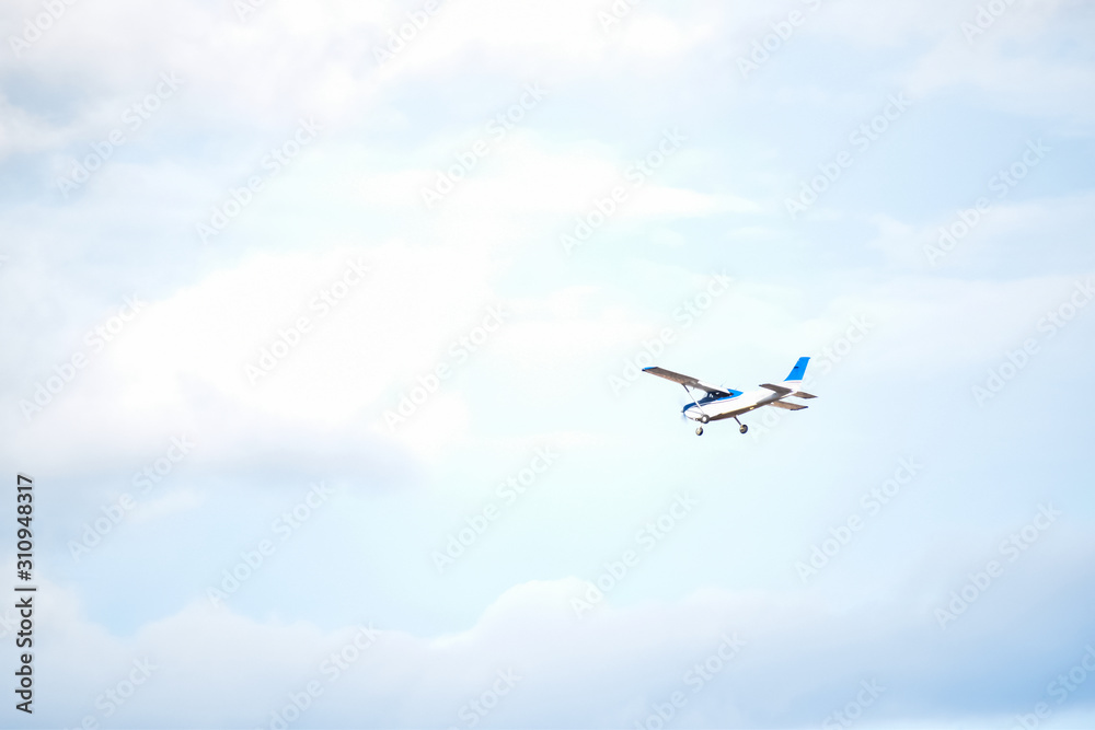 Light plane flying over a little cloudy blue sky