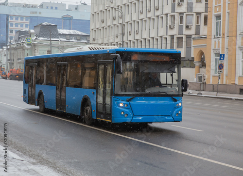 bus moves in winter in snowfall on a city