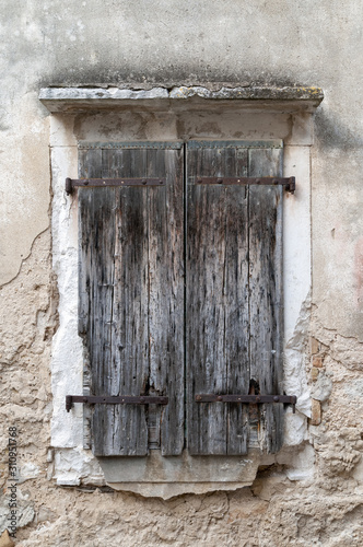 Old and wooden and rustical closed window on the destroyed wall. Croatia.