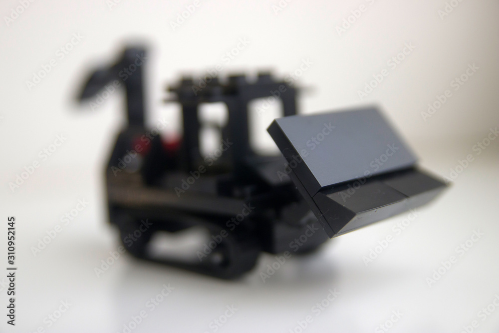 Fototapeta premium black toy bulldozer from designer cubes on white background close up