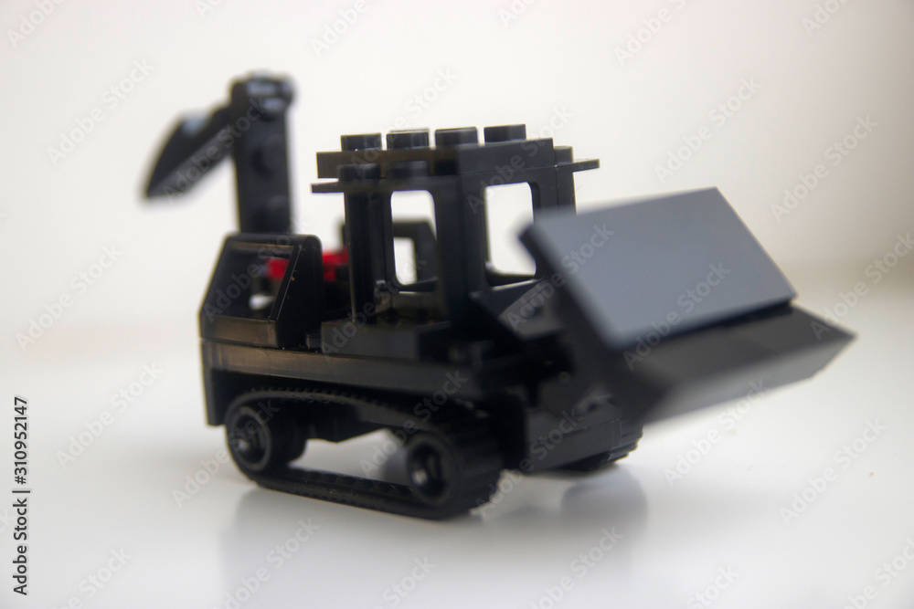 black toy bulldozer from designer cubes on white background close up