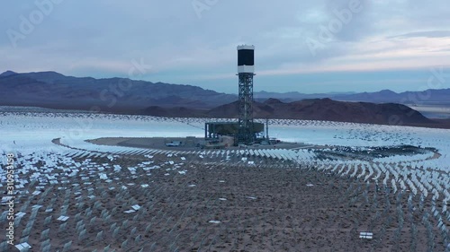 Aerial orbit shot of solar power towers, heliostat mirrors with sun reflections photo