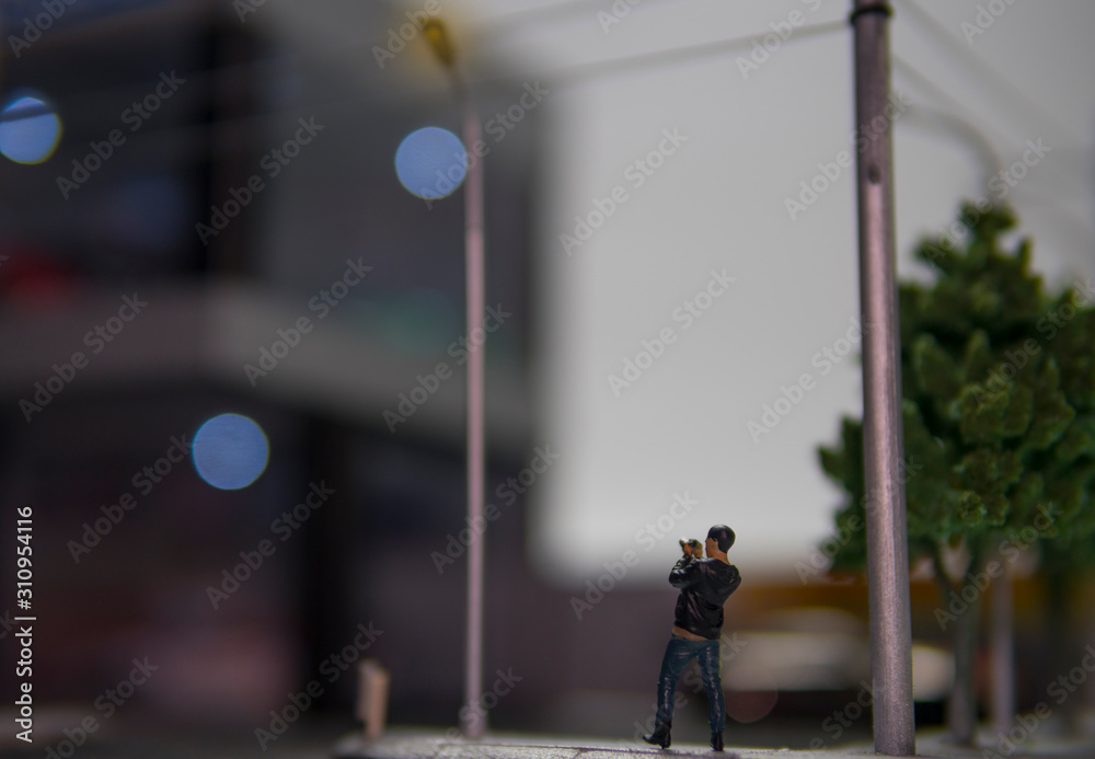 Selective focus of doll figure adult man standing holding camera with blurred background. Selective focus of doll figure adult man standing holding camera with blurred background.