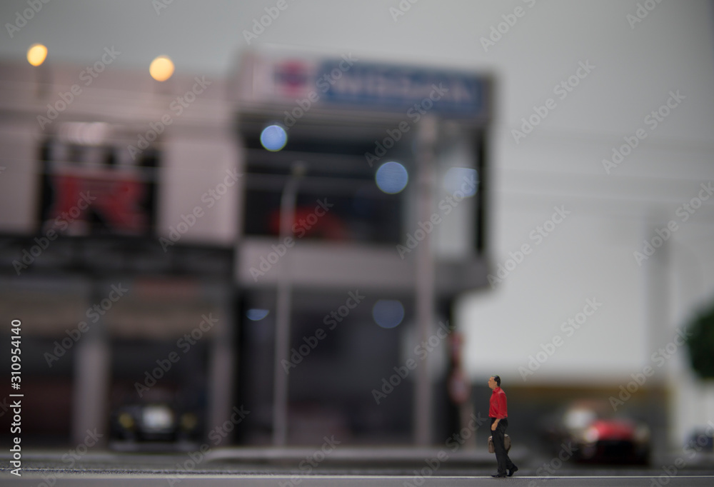 Obraz premium Selective focus of doll figure adult man walk along pedestrian walkway with blurred background.
