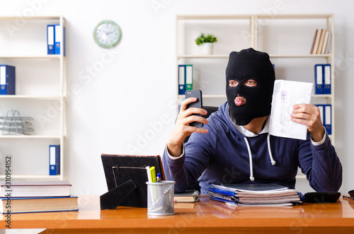 Male thief in balaclava in the office