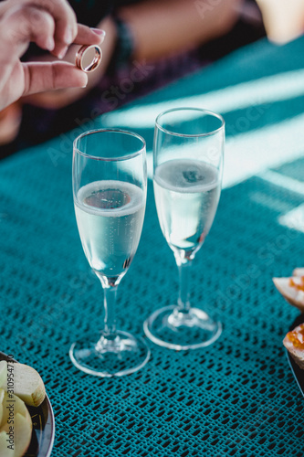 Hand putting ring in wedding glass with sparkling champagne
