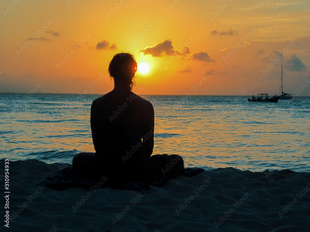 young woman at sunrise meditates on the beach. Playa del Carmen Mexico caribbean sea. Woman in yoga position and relax