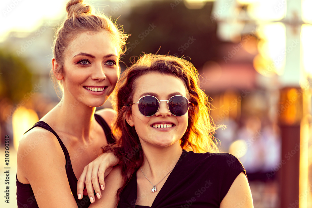 Close up portrait of young female couple. Two attractive girls looking aside while relaxing outdoors, admiring sunset. Lesbian lives, travel concept. Love is love. Horizontal shot. Selective focus Close up portrait of young female couple. Two attractive girls looking aside while relaxing outdoors, admiring sunset. Lesbian lives, travel concept. Love is love. Horizontal shot. Selective focus