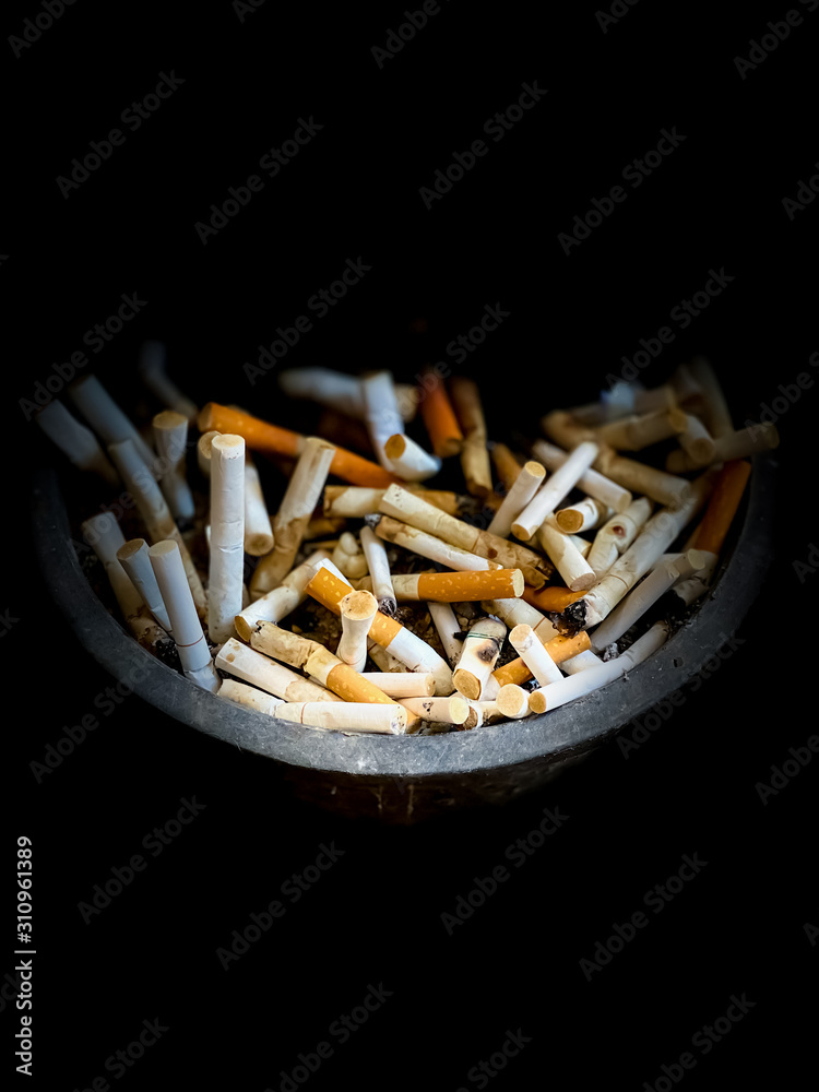 Cigarette butts in an ashtray in dark scene wallpaper backgrounds Cigarette butts in an ashtray in dark scene wallpaper backgrounds