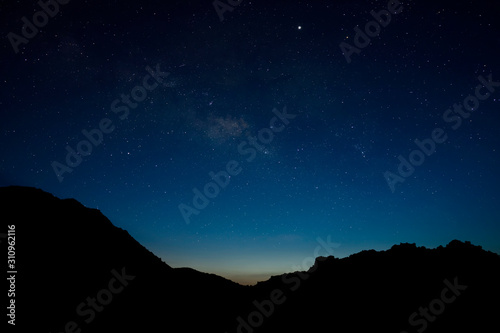 The blue sky with star is above the silhouette mountain in the twilight after sunset