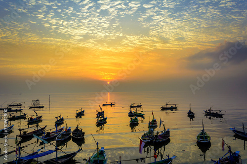 fishermen boats at sunrise on beach in surabaya, indonesia