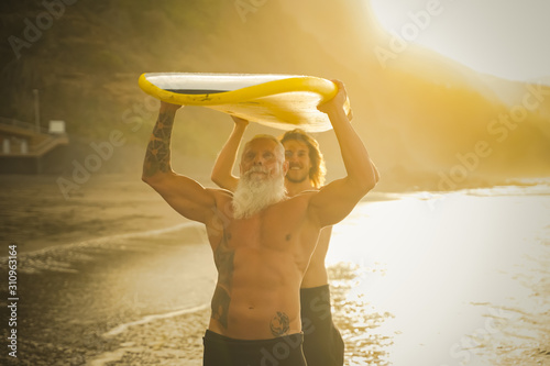 Father and son doing surfing in the summer time . People going out into the ocean. Sporty people lifestyle and extreme sport concept - Image