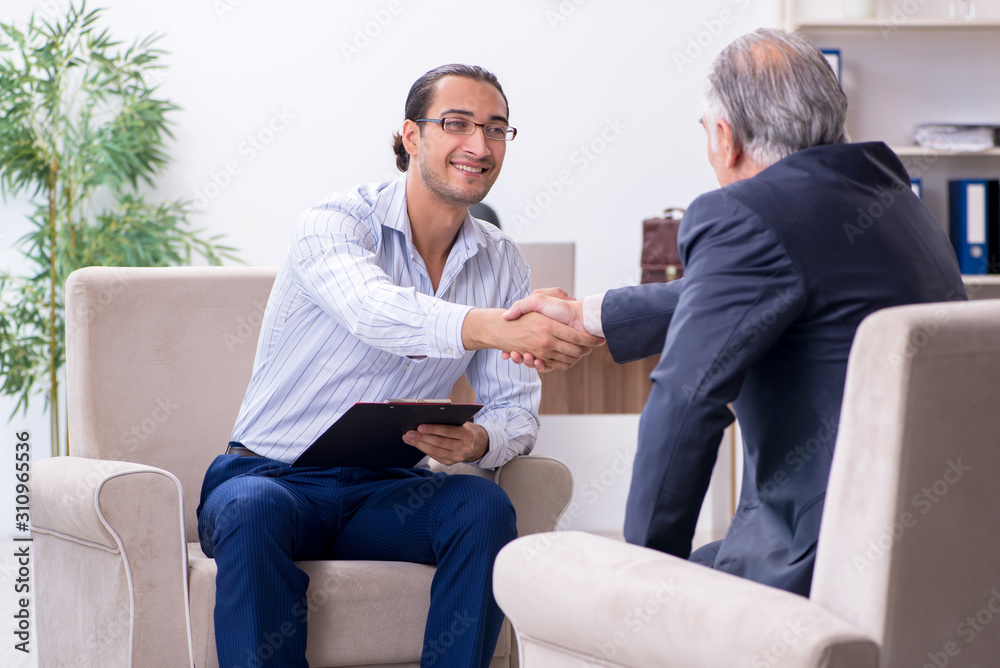 Old man visiting young male doctor psychologist Old man visiting young male doctor psychologist