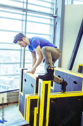 young handsome man doing parkour in gym inside, lifestyle sport people concept