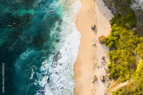 View from above, stunning aerial view of a rocky shore with a beautiful beach bathed by a rough sea during sunset, Nyang Nyang Beach (Pantai Nyang Nyang), South Bali, Indonesia. photo