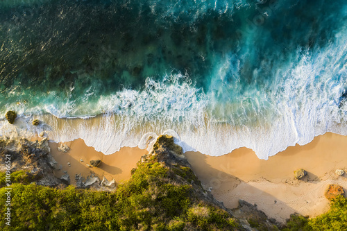 Obraz na płótnie View from above, stunning aerial view of a rocky shore with a beautiful beach bathed by a rough sea during sunset, Nyang Nyang Beach (Pantai Nyang Nyang), South Bali, Indonesia. w salonie