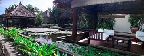 Outdoor bungalows for rest and relaxation on the ocean. Around the bungalows are pools with blooming water lilies.