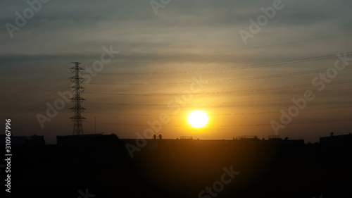 sunset in the city with silhouette of High voltage pole