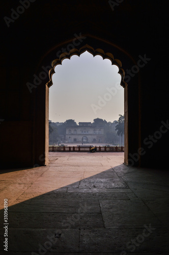 A mesmerizing view with sun rays create dramatic light and shadow of inside the hall of safdarjung tomb memorial from the main gate entrance at winter morning.