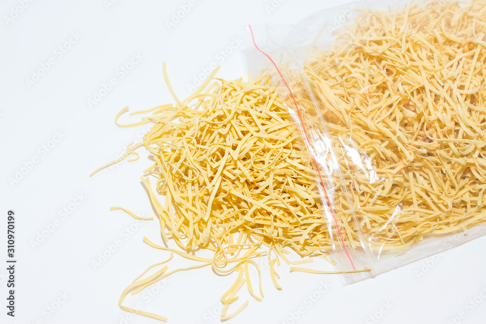 Homemade egg noodles in a plastic bag on a white background. Homemade egg noodles in a plastic bag on a white background.